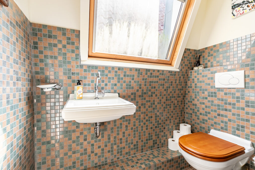Modern bathroom with tiled walls and skylight window.