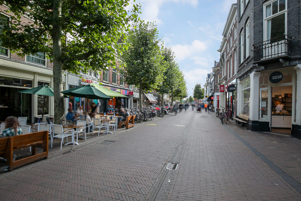 Busy street with cafes and bicycles on sidewalk.