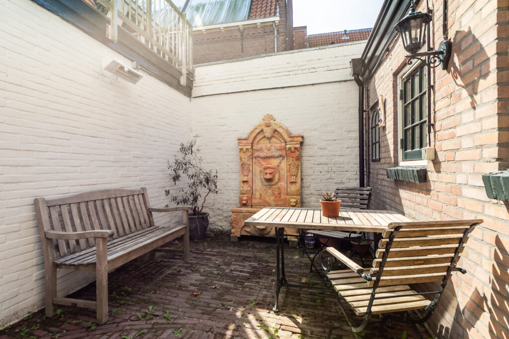 Cozy patio with fountain and wooden furniture.
