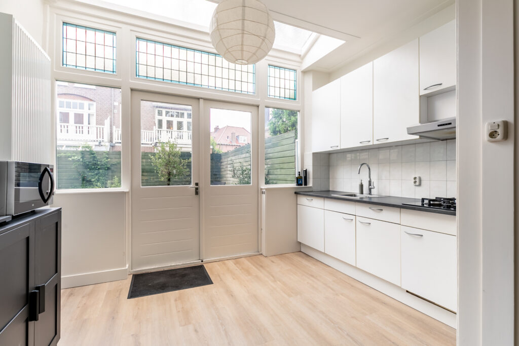 Bright modern kitchen with white cabinets and large windows.