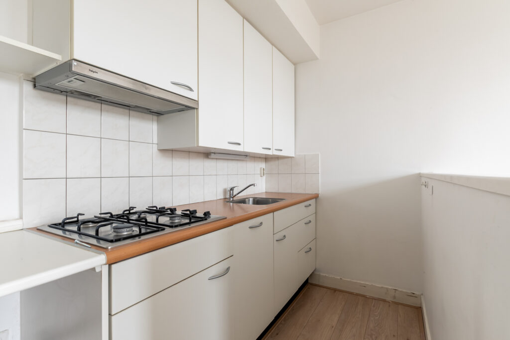 Modern white kitchen with wooden countertops and stove.