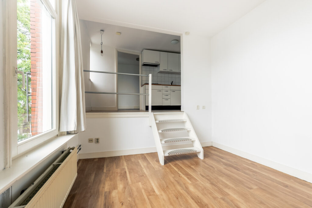 Empty room with stairs to small kitchen