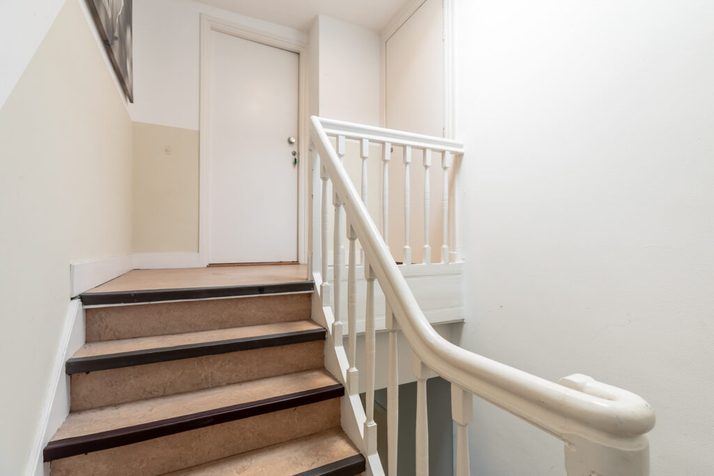 Indoor staircase with white railing and closed door.