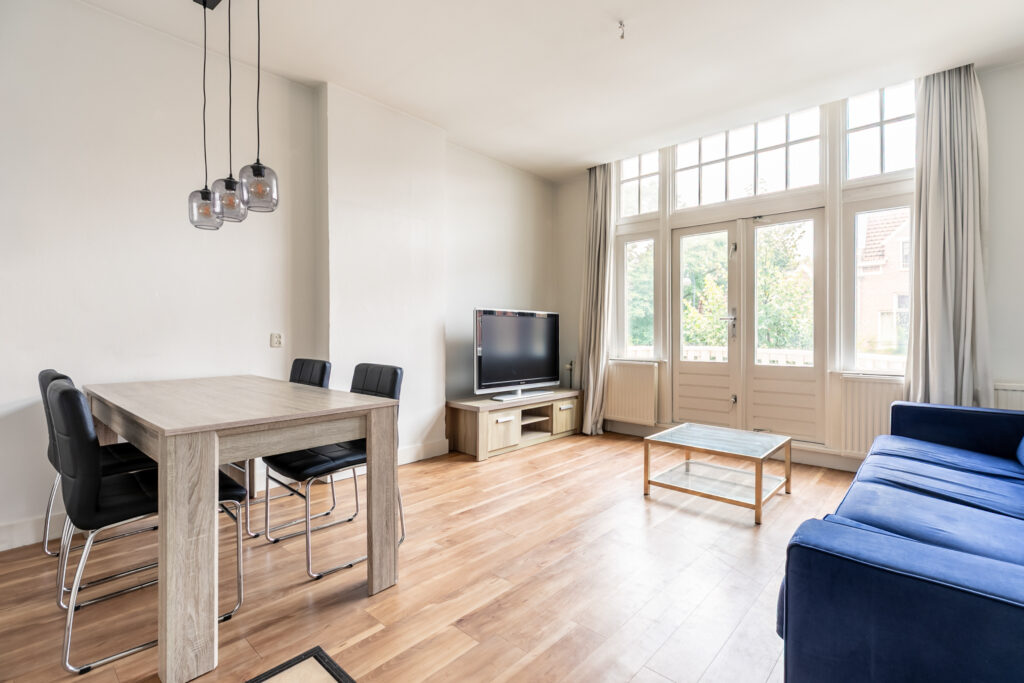 Modern living room with table, TV, and blue sofa.