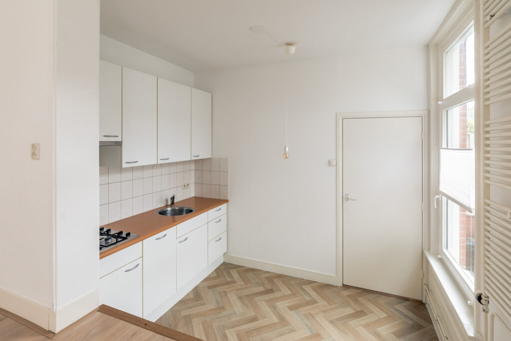 Minimalist kitchen with white cabinets and wood countertop.