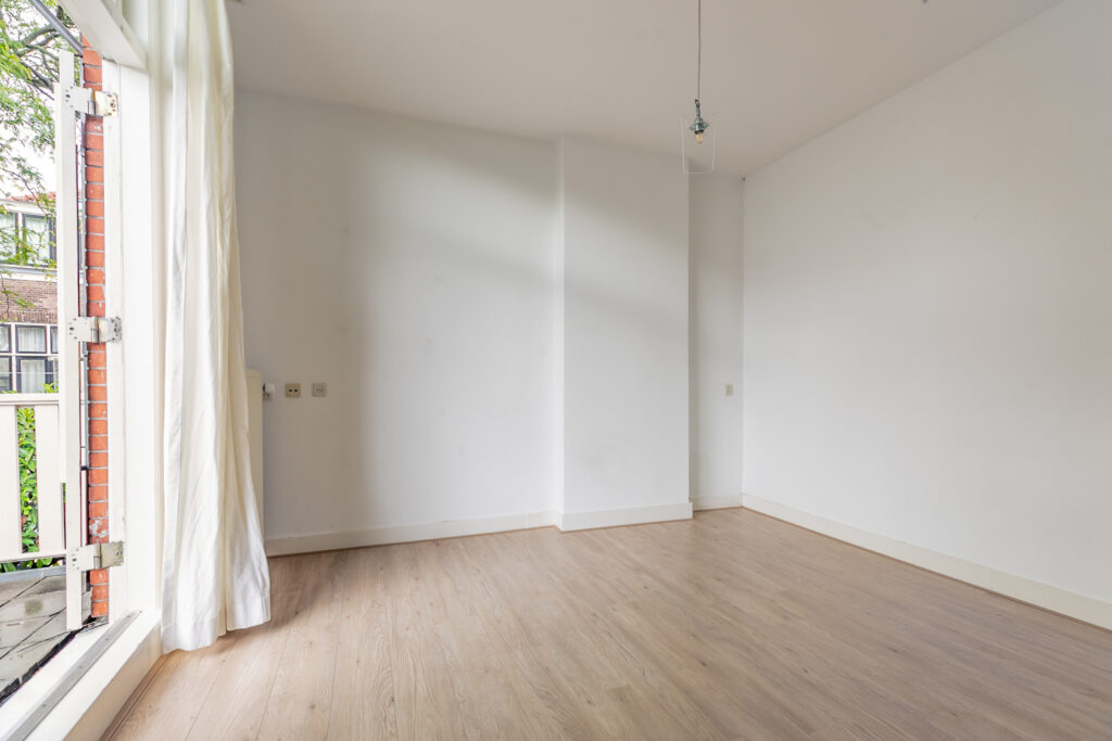 Empty room with wooden floor and large window.
