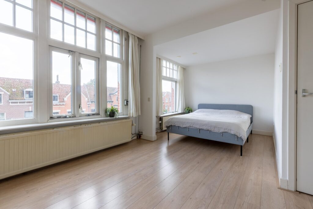 Bright bedroom with large windows and bed.