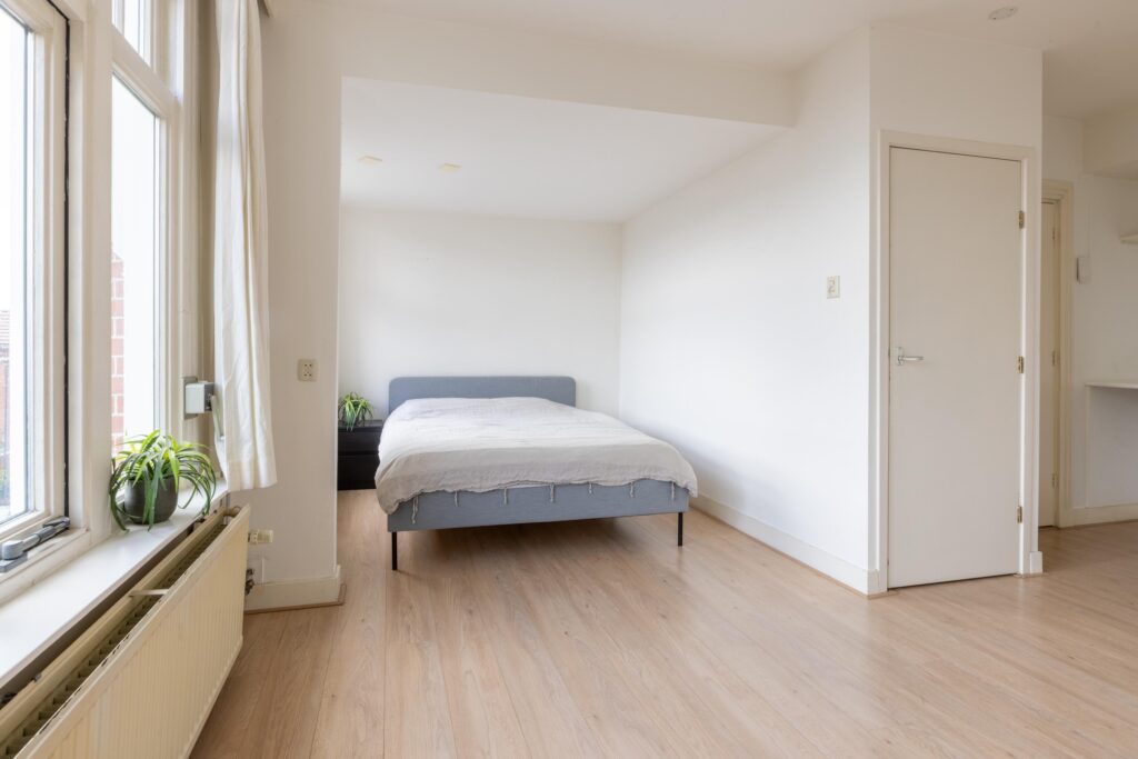 Minimalist bedroom with hardwood floor and large window
