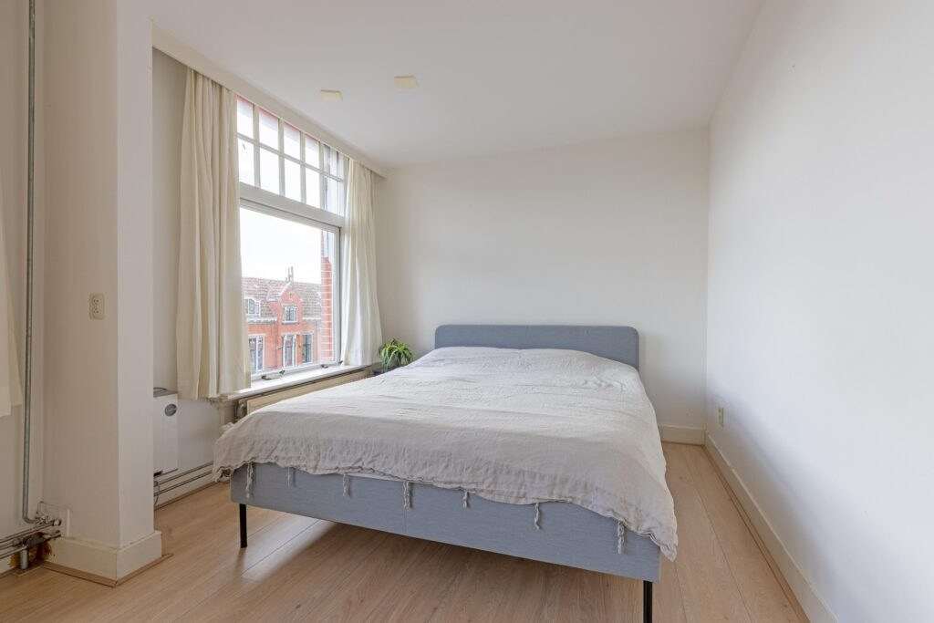 Minimalist bedroom with large window and bed.