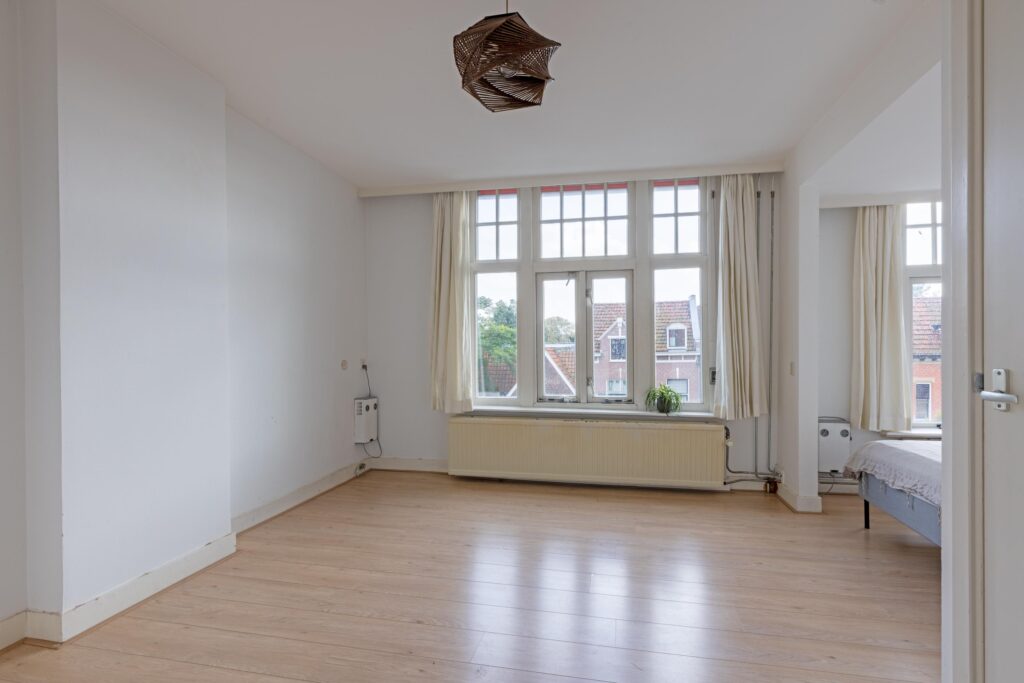 Spacious room with large windows and wooden floor.