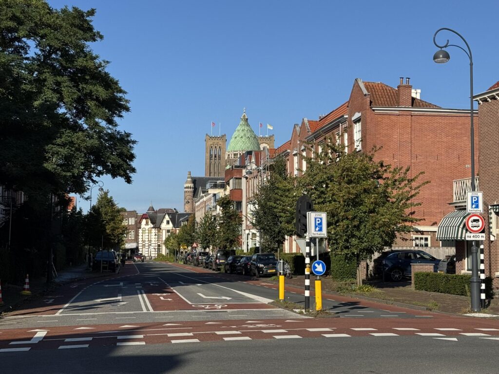 Residential street with church tower and blue sky.