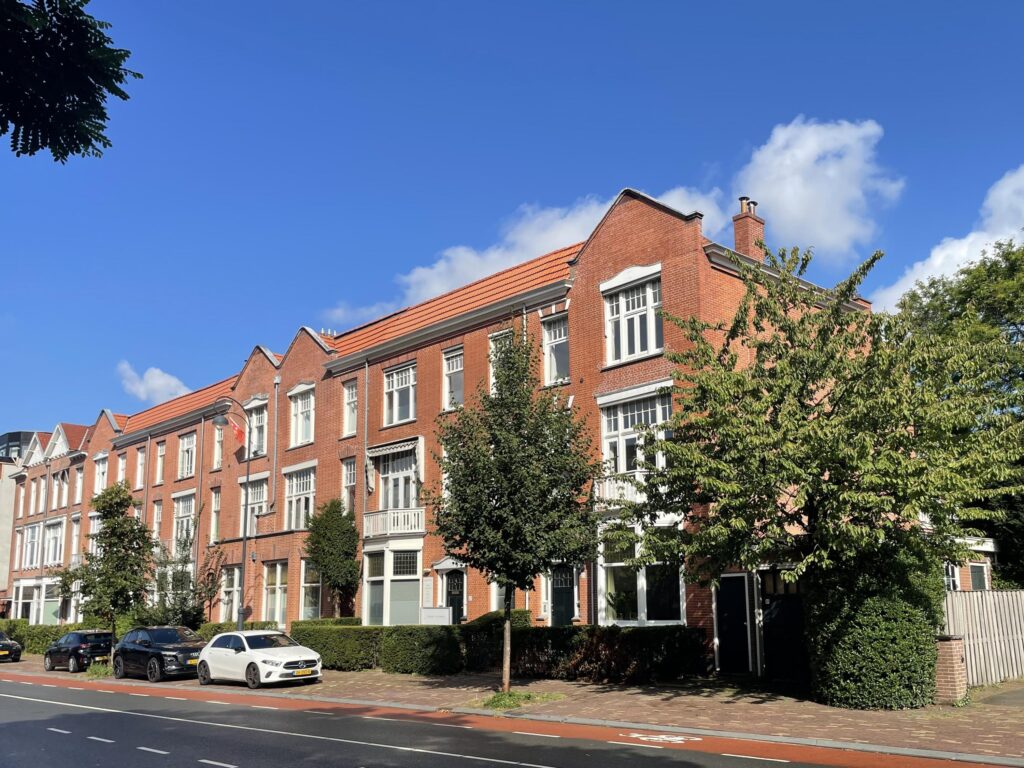Row of red-brick buildings with parked cars.