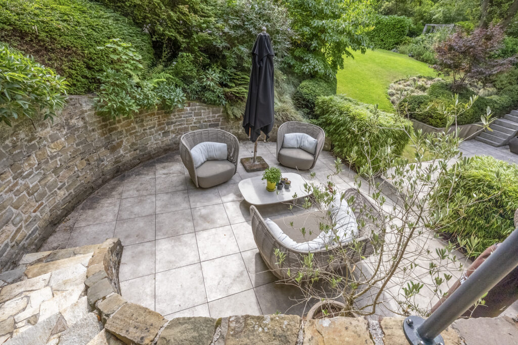 Cozy garden patio with chairs and greenery.