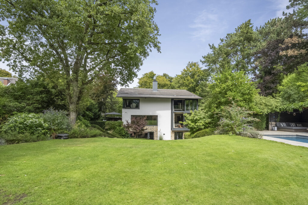 Modern house with large garden and trees.