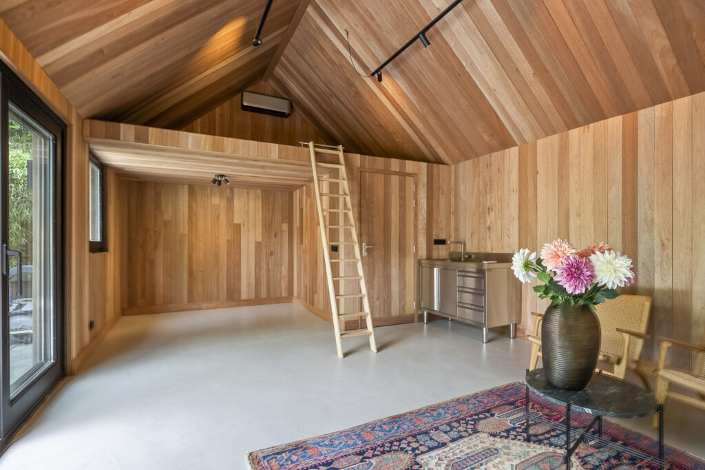 Wooden interior with loft, ladder, and floral arrangement.