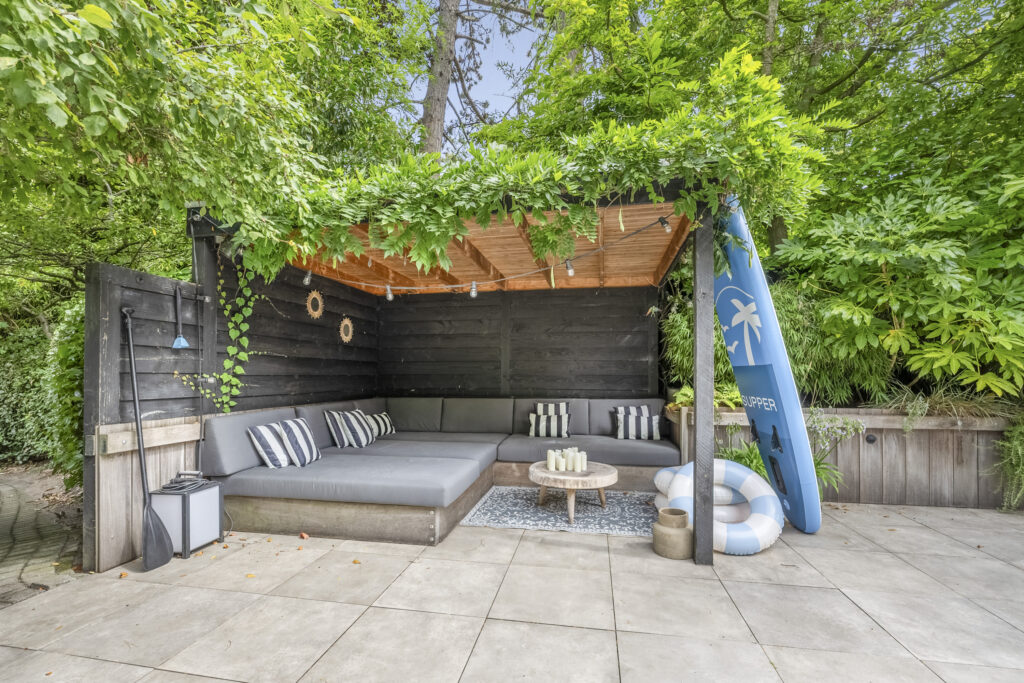 Cozy outdoor patio with lush greenery and sofa.