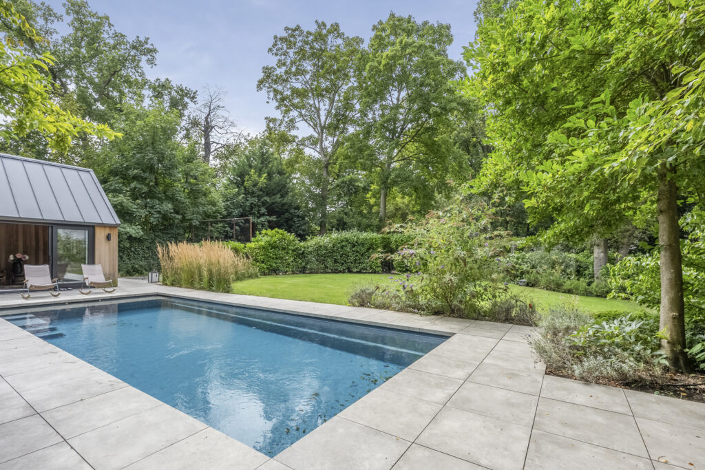 Modern poolside patio with lush greenery view