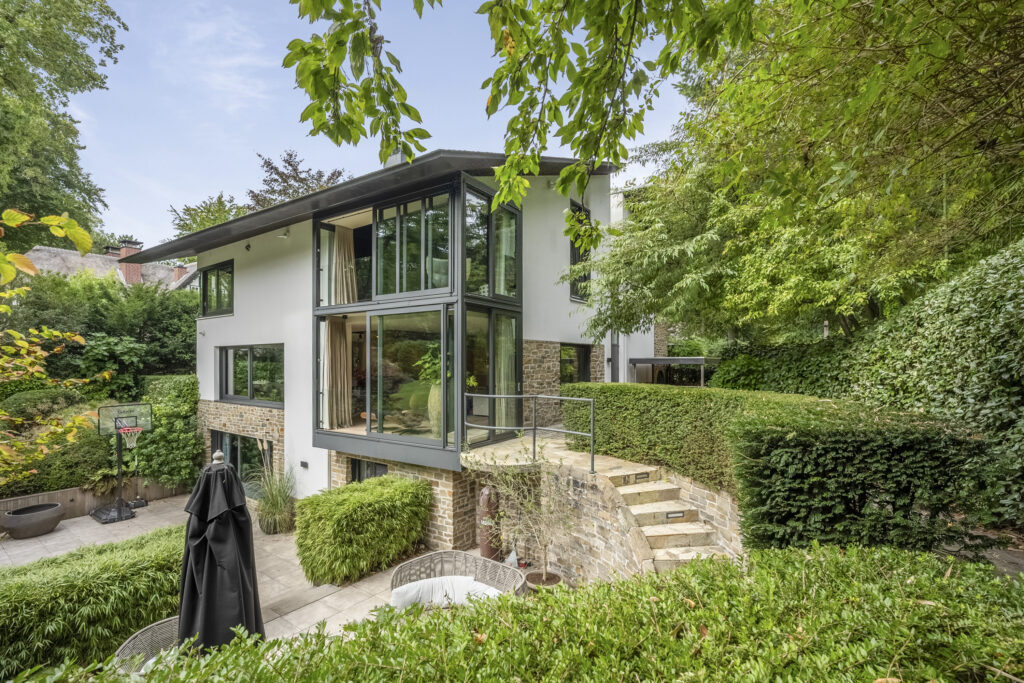 Modern house with large windows and lush greenery.