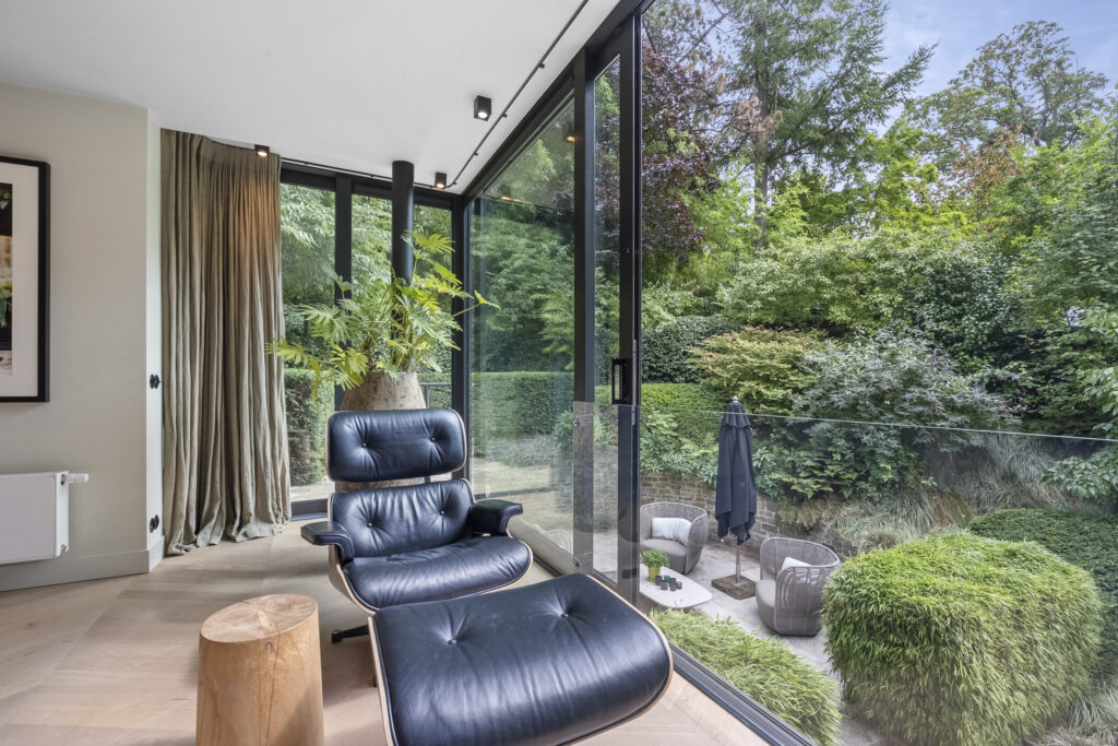 Modern chair by window overlooking lush garden.