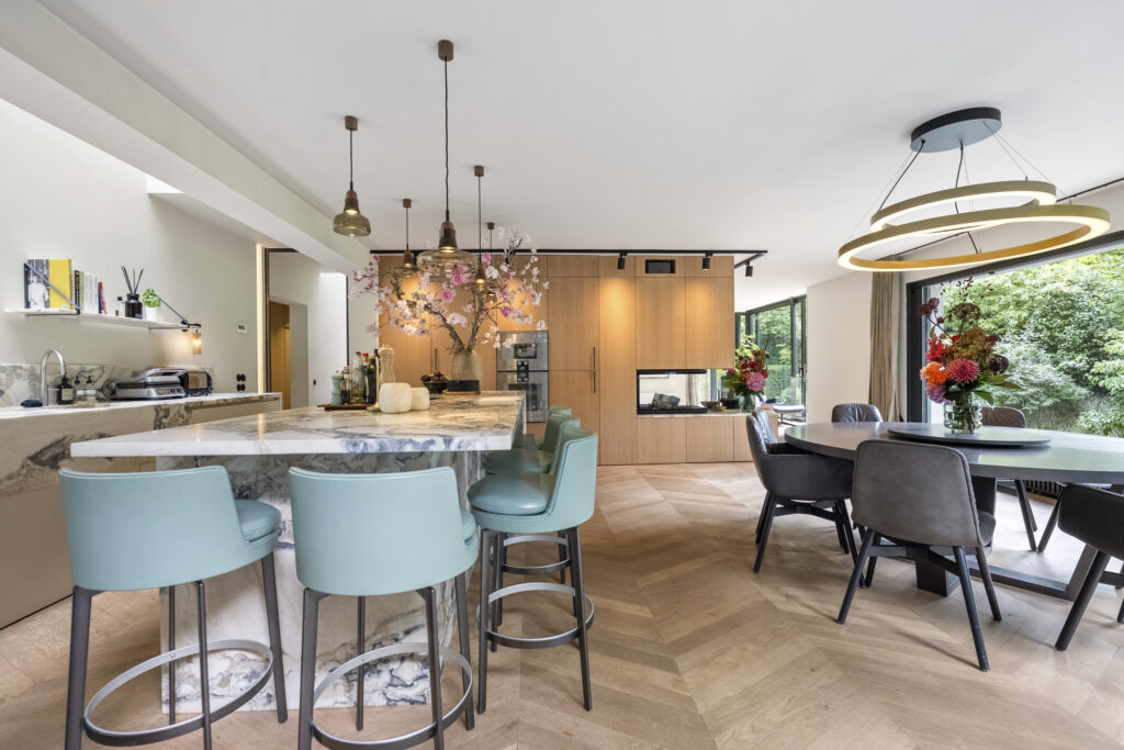 Modern kitchen with marble island and teal stools.