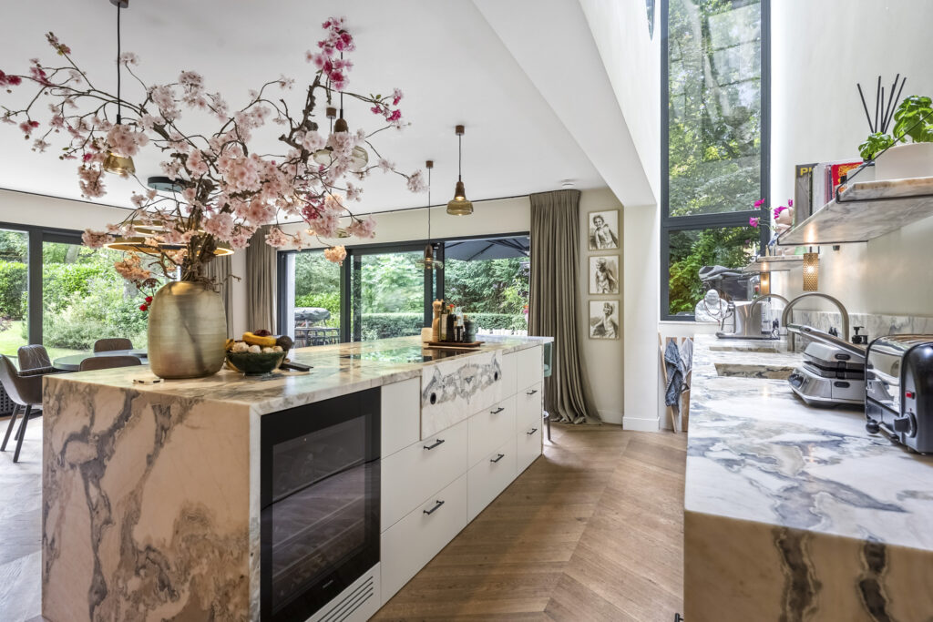 Luxury kitchen with marble countertops and large windows.