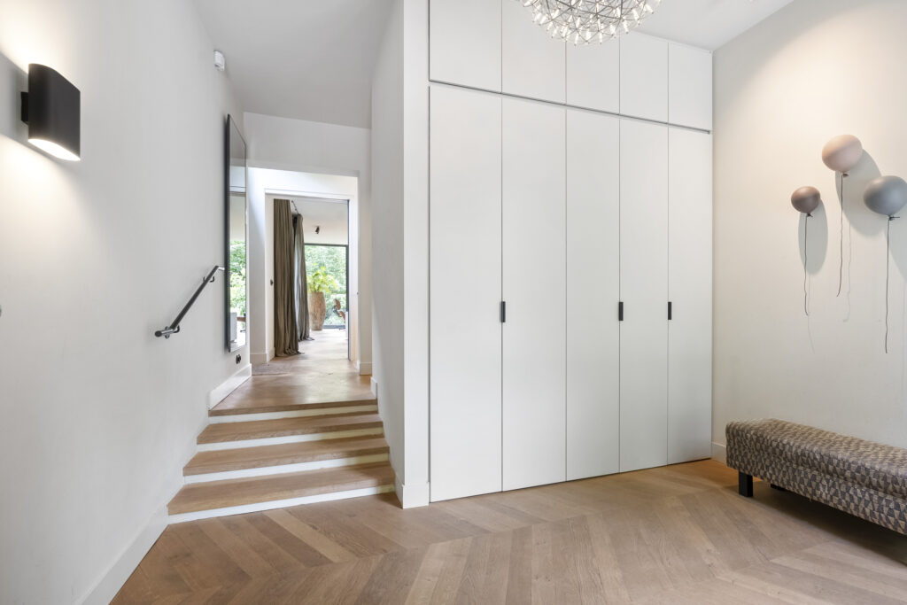 Modern hallway with wooden floor and white cabinets