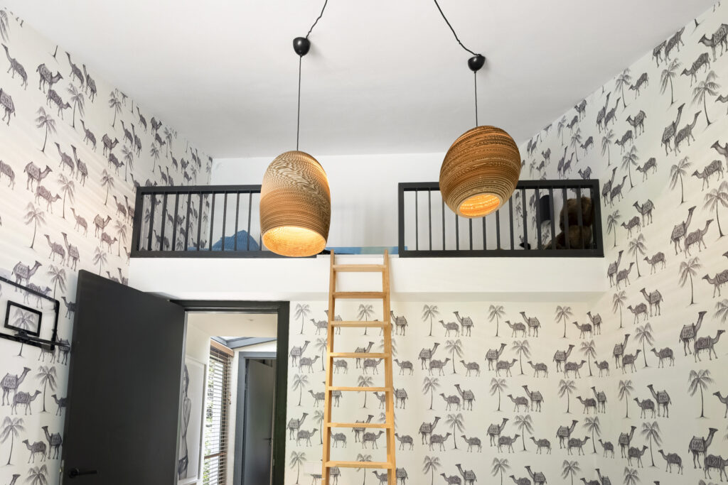 Loft room with camel wallpaper and hanging lights.