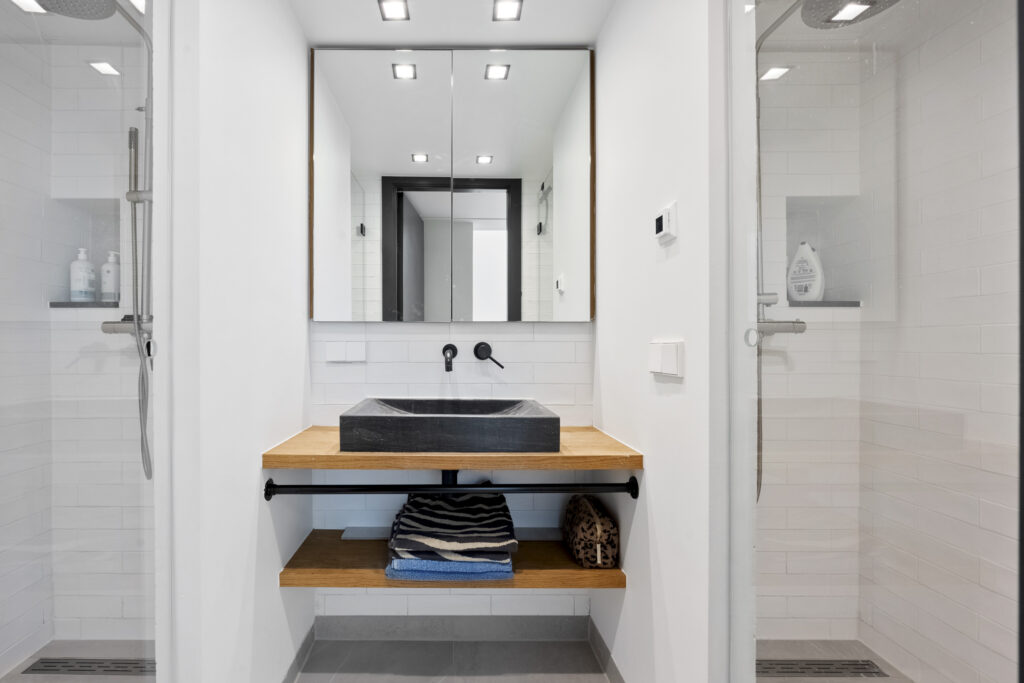 Modern bathroom with black basin and two showers.