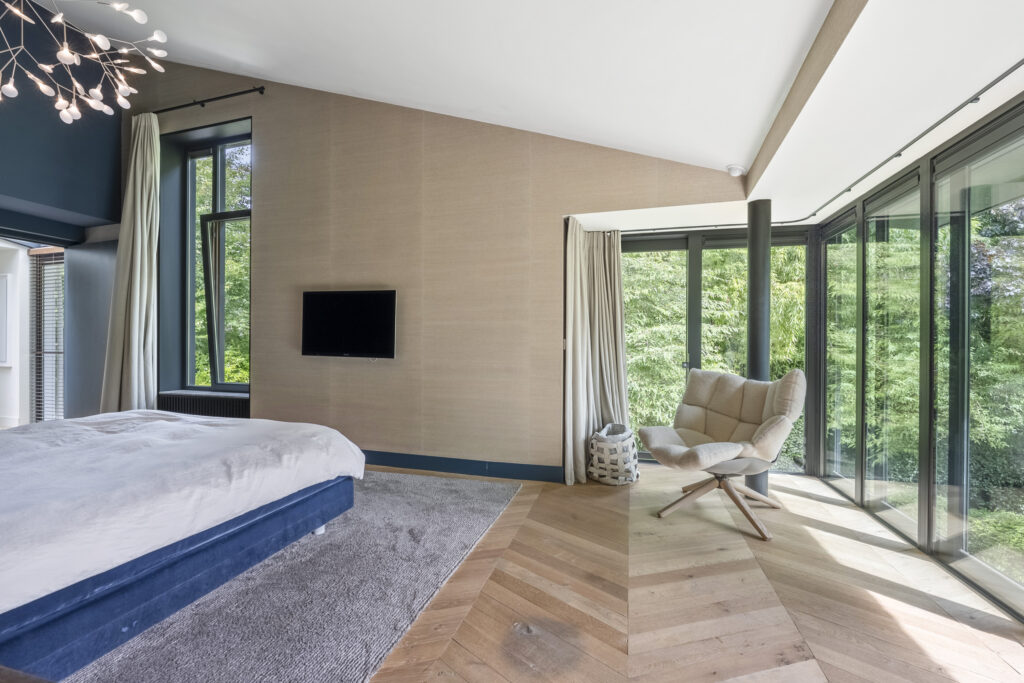 Spacious bedroom with modern decor and large windows.