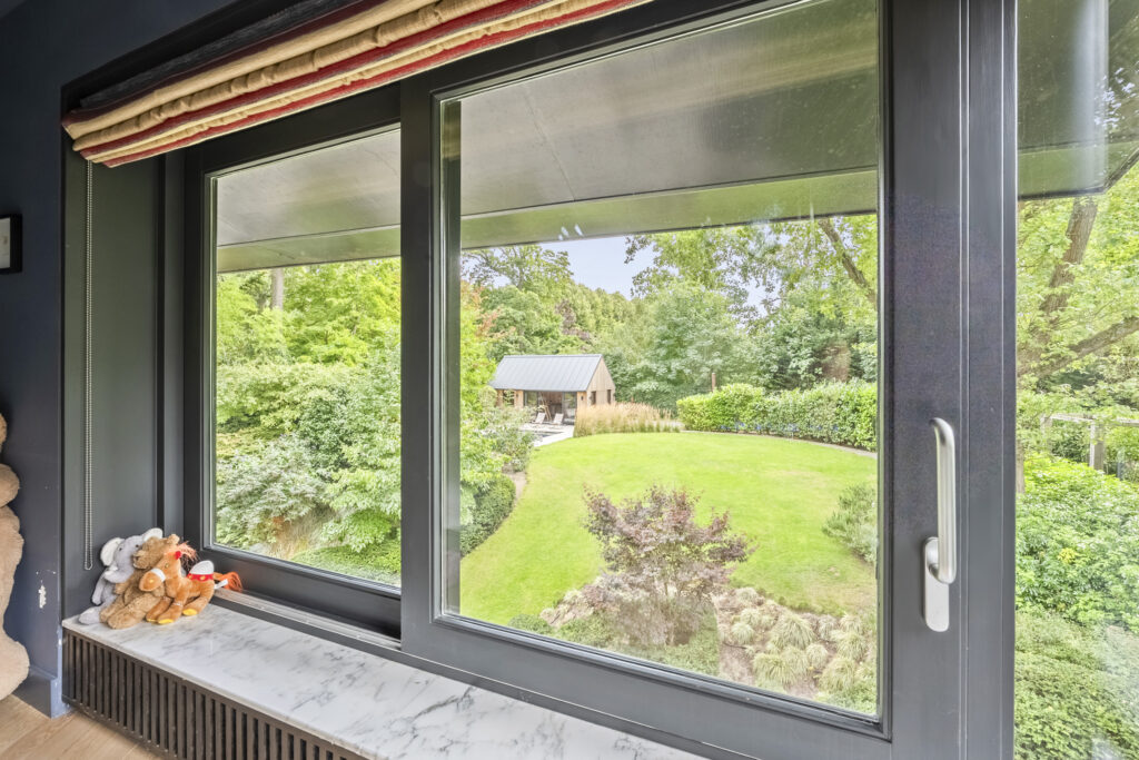Garden view through modern window with toys on sill.