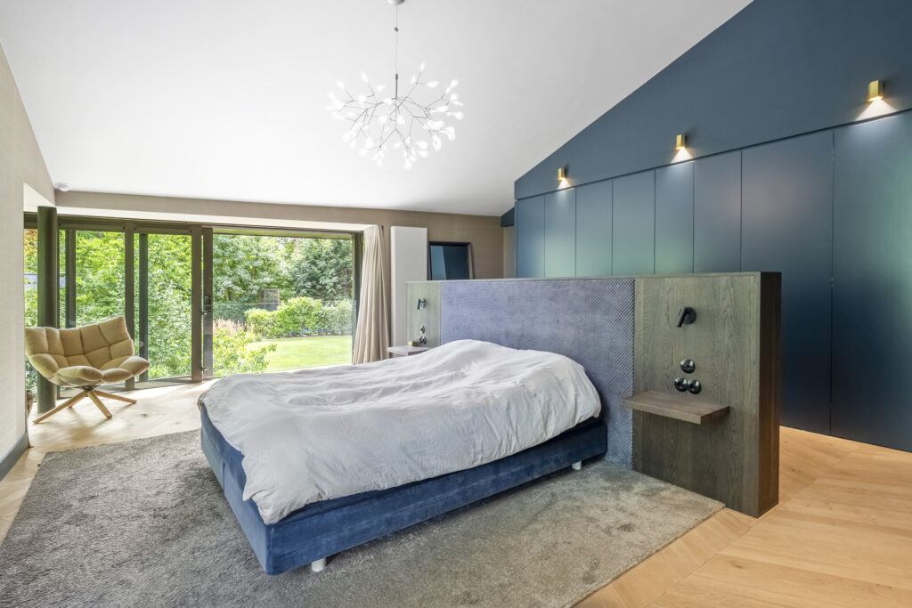 Modern bedroom with large windows and garden view.