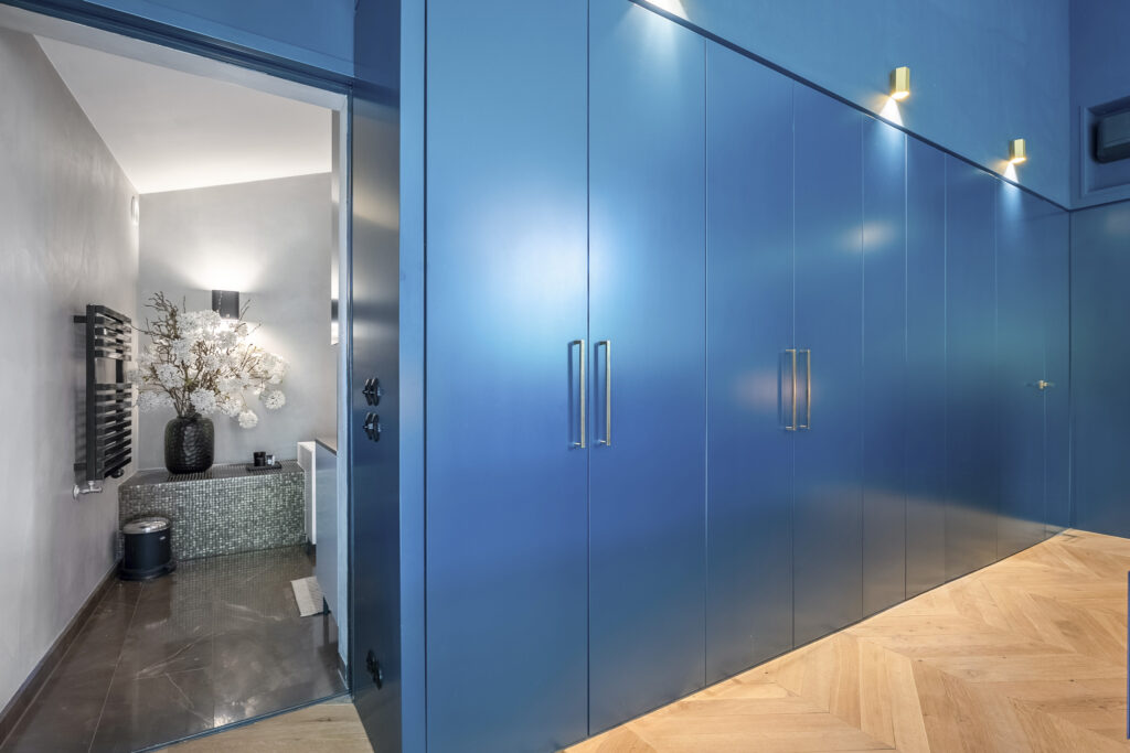 Blue hallway with open door to modern bathroom.