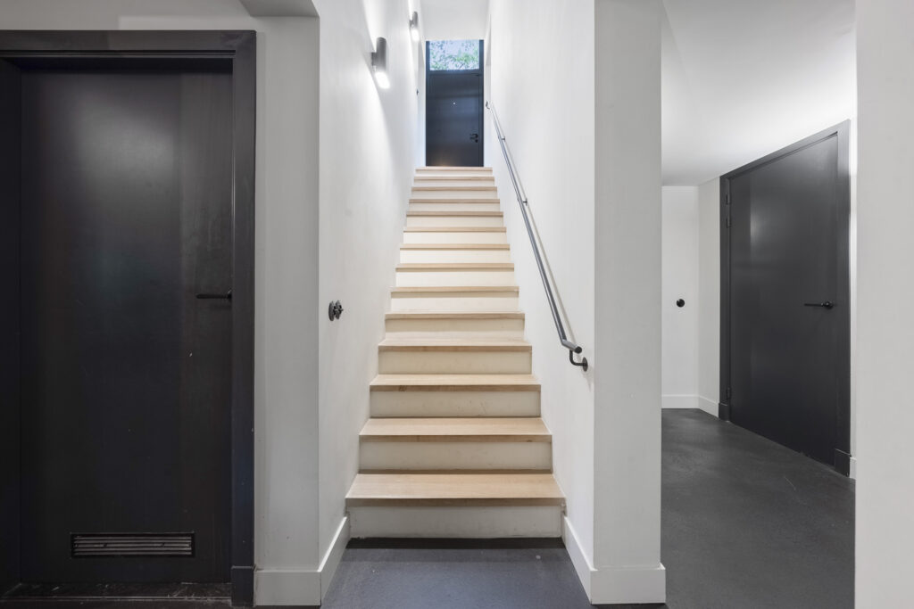 Modern staircase with black doors and white walls.