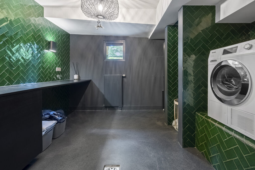 Modern laundry room with green tile walls.