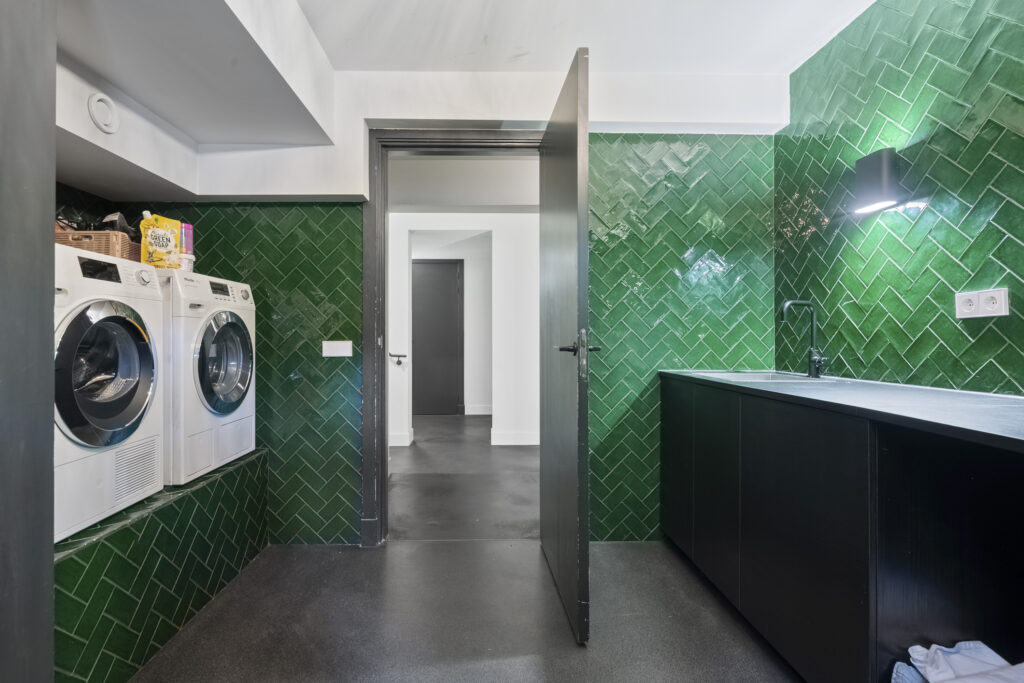 Modern laundry room with green tile walls.