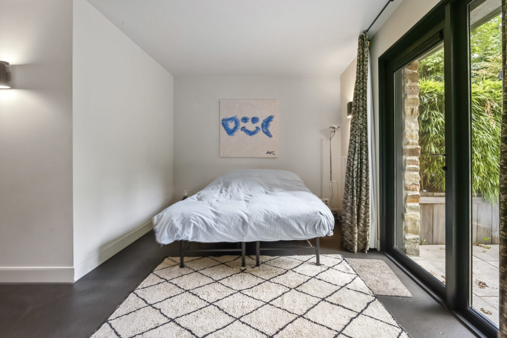 Modern bedroom with large window and abstract art.