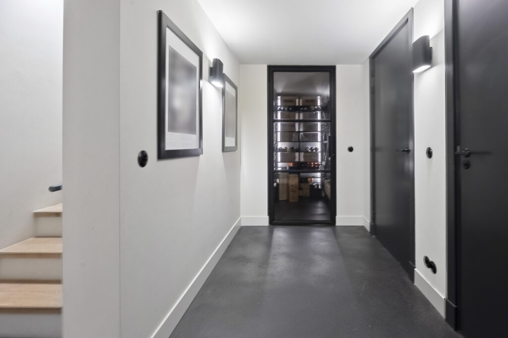Modern basement hallway with wine storage behind glass door