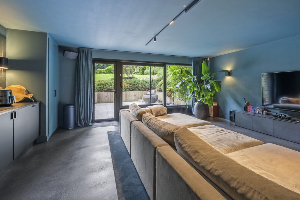 Modern living room with large windows overlooking garden.