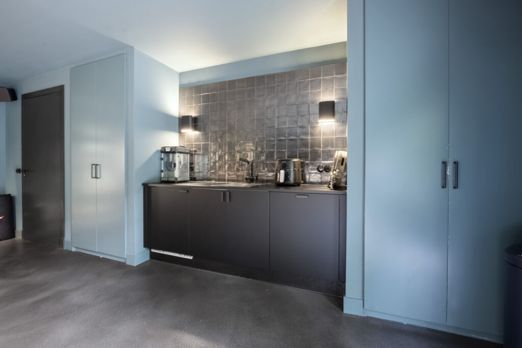 Modern kitchenette with appliances and tiled backsplash.