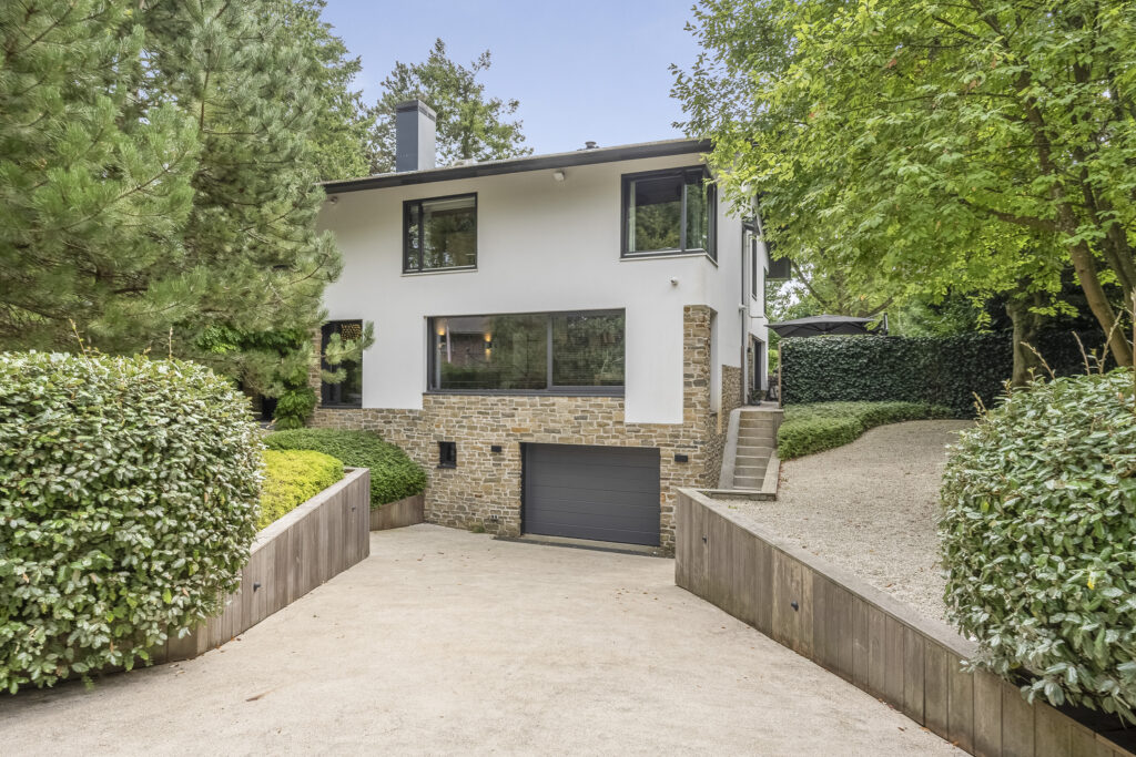 Modern house with driveway and lush greenery