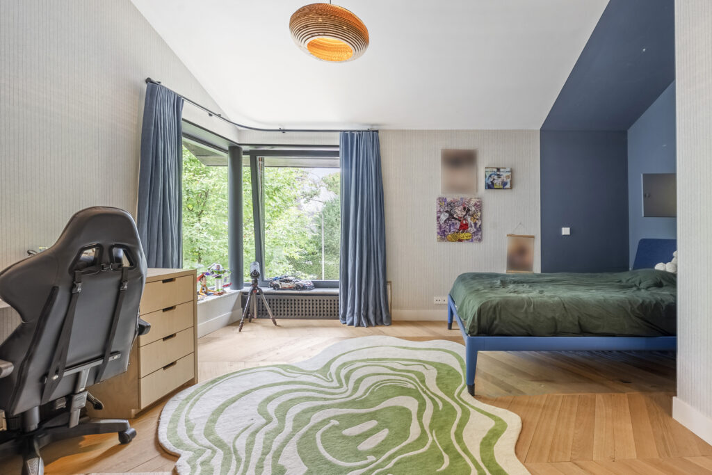 Modern bedroom with large window and green bedspread.