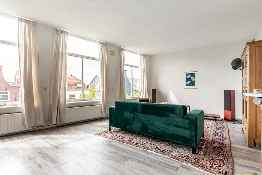 Bright living room with green sofa and large windows.