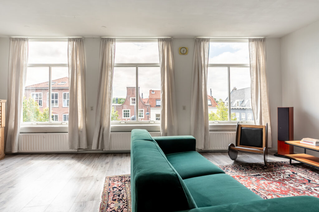 Bright living room with large windows and green sofa.