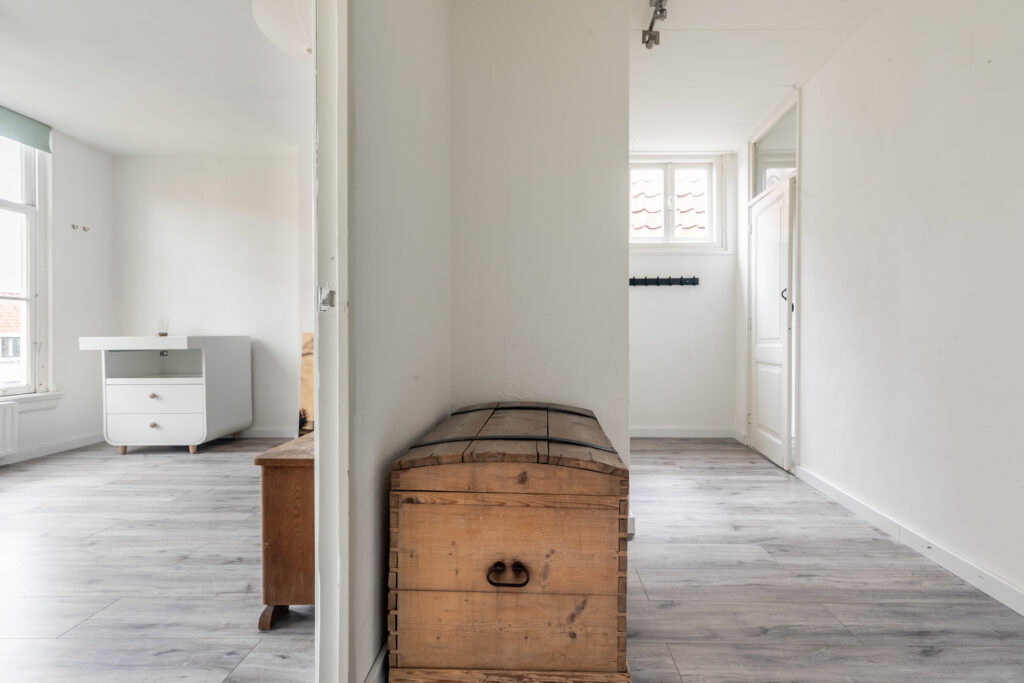 Minimalist room with wooden chest and white dresser.