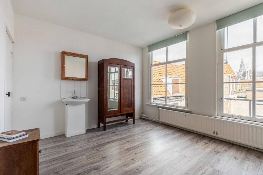 Empty bright room with wooden furniture and large windows.