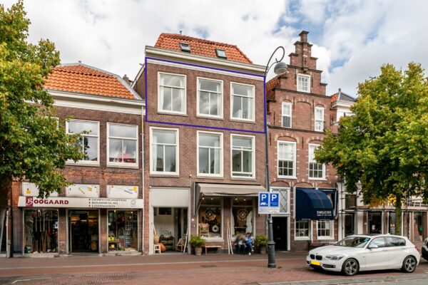 Historic Dutch building with shops and parked car.