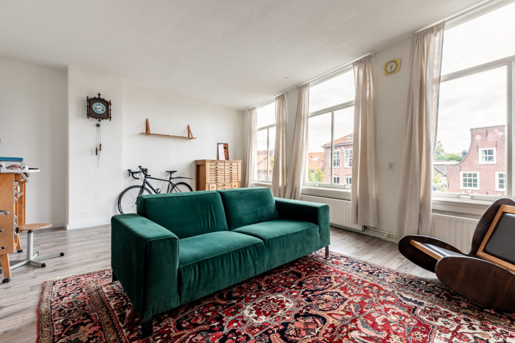 Bright living room with green sofa and bicycle.