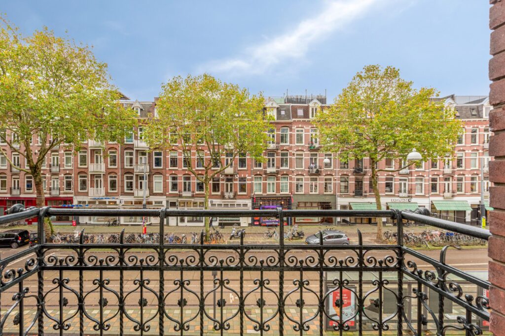 View of street from balcony with trees and bikes.