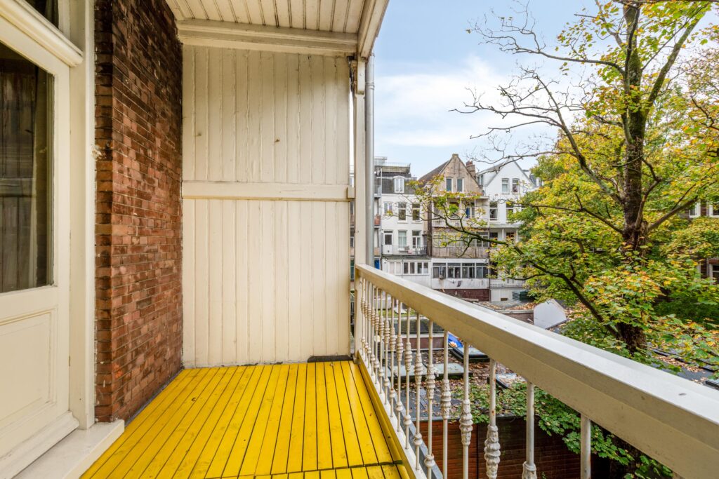 Cozy balcony with yellow wooden floor and city view.