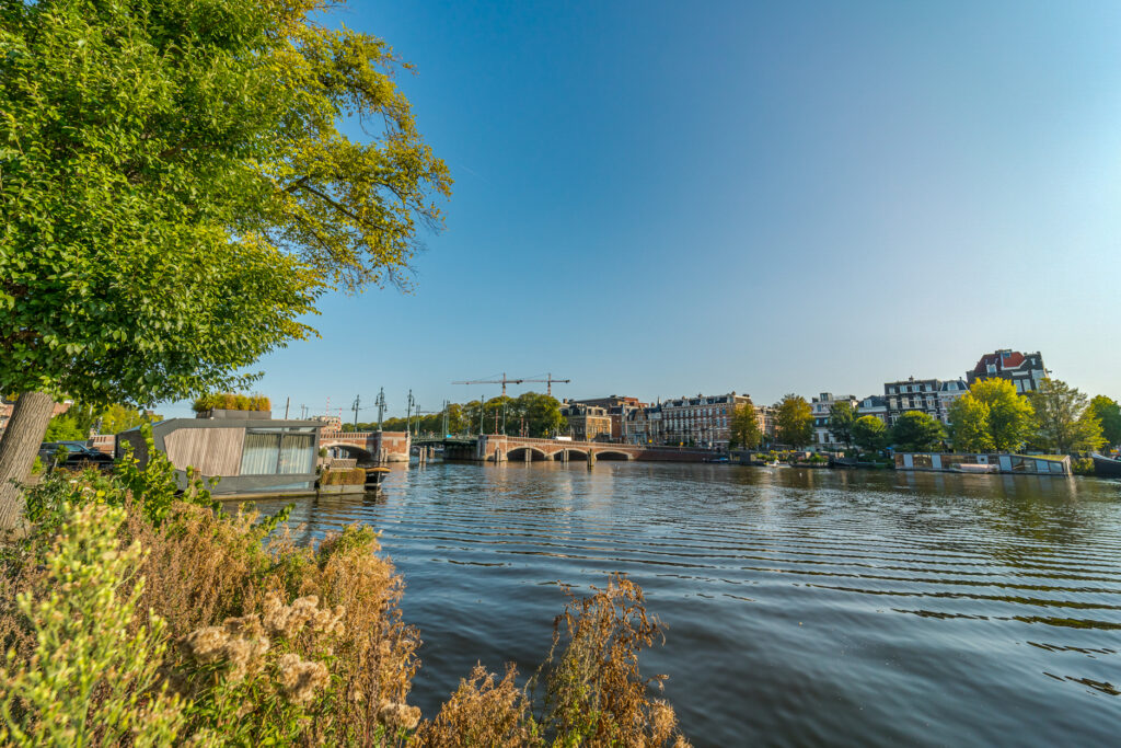 Scenic riverside with bridge and houseboats in Amsterdam.